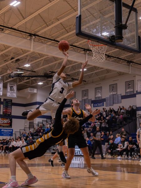 Being blocked by two members of the opposing team, sophomore Jamarious Britt attempts to jump over them to make a basket. Britt had no other choice but to jump above the two players to get past them. 
