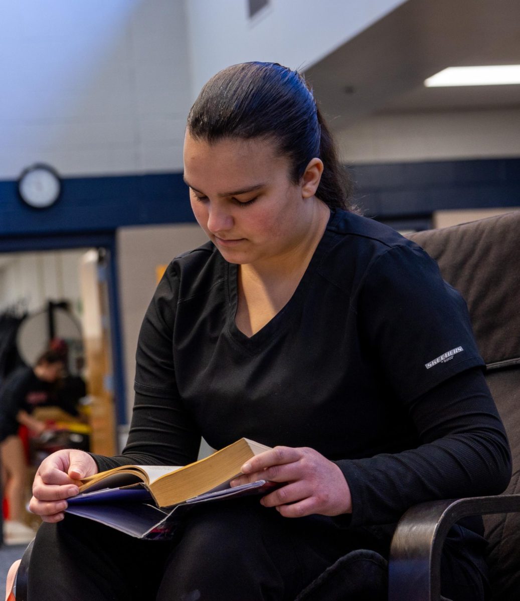 Sitting in a library chair, junior Annalisse Webber reads the last few chapters of her book. One of Webber's favorite pastimes is reading and enjoying the library's atmosphere. 
