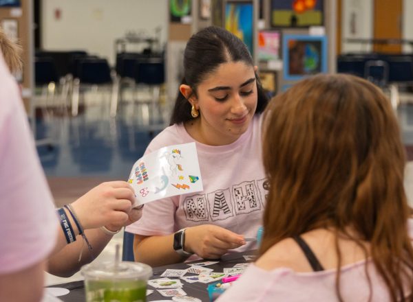 Watching her work, junior Kristina Karami creates a design to be put onto a button. After having helped set up many of the stations and artwork, Karami enjoyed creating her own artwork at the stations before the Fine Arts Festival was opened to the public on April 4.