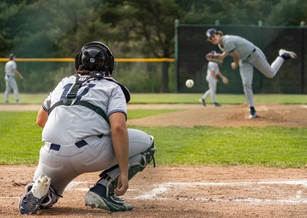 Senior Owen Meyer squats as he catches the ball thrown by pitcher sophomore Lucas Williams. Before each inning starts the pitcher and catcher are allowed a few practice throws to get both players ready. 