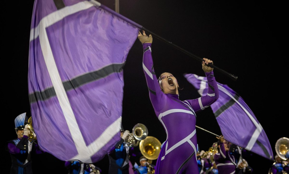 During halftime at a varsity football game, junior Chloe Hearn flips a bright purple flag in the air. This school year, the theme for both the Spartan Regiment and the Color Guard was about the Gateway Arch.