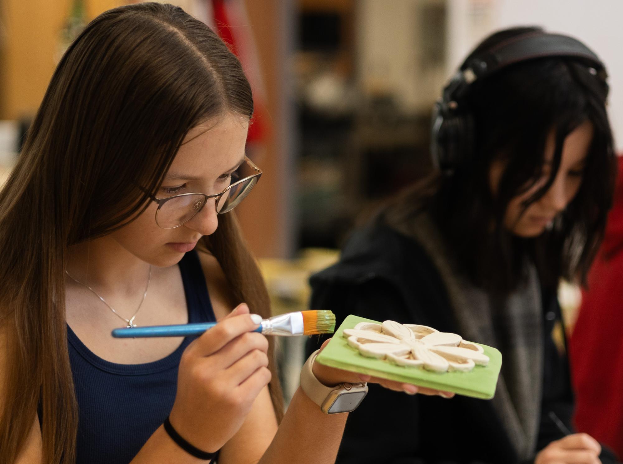 Junior Rachael Latzel applies a vibrant green coating to her floral-designed ceramic slab, leaving the top layer bare for the addition of more colors. When glazing ceramics, three thick coats is the suggested amount, to ensure the piece is highly pigmented.
