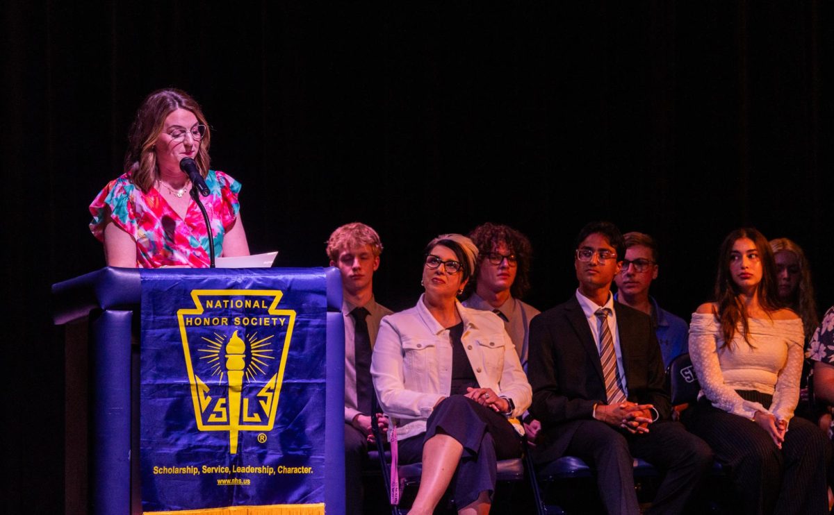Mrs. Sarah LaRue, an English teacher, speaks out to the crowd during her commencement speech, encouraging greatness from the new inductees. The current board members, Dr. Suzanne Leake, and the incoming board members sat behind the podium to listen to the speech with admiration. 