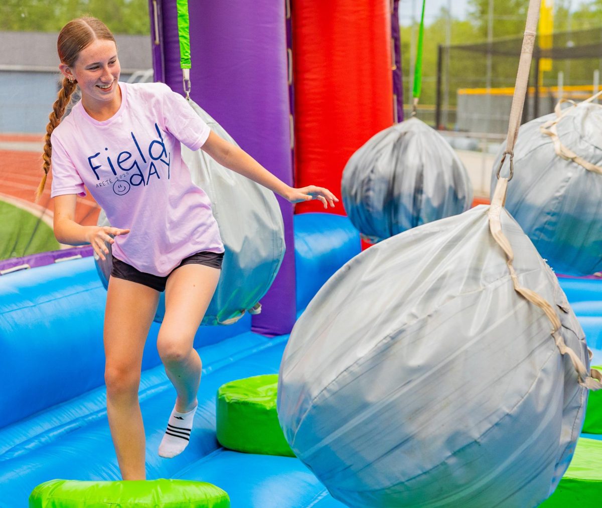 Sophomore Briana Stoesz jumps between platforms while her friends throw rocks at her. Committee members typically play the games and on the inflatables after they’ve finished setting up.