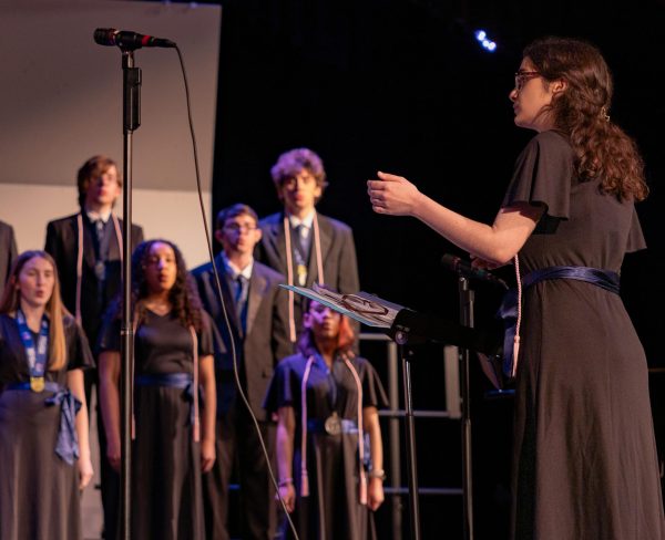 Conducting the Chamber Choir during its final performance on May 12, senior Katie Garrett motions to the singers of her arrangement of Lizzy McAlpine's "Give Me A Minute." Garrett is the first student in the choir program's history to arrange a song for the choirs to perform. 
