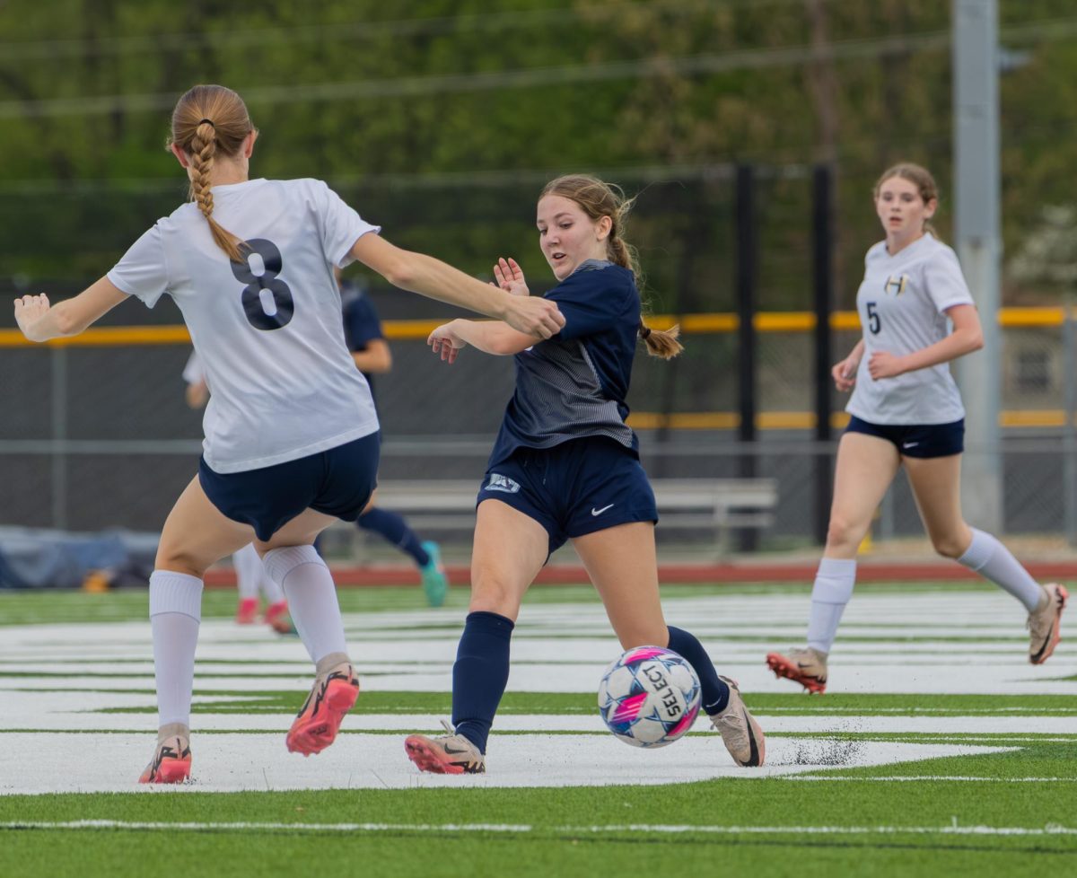 As a defender stands in front of senior Genna Valenti, she dribbles the ball around her. Valenti was able to get past the defender and pass to a nearby teammate. 
