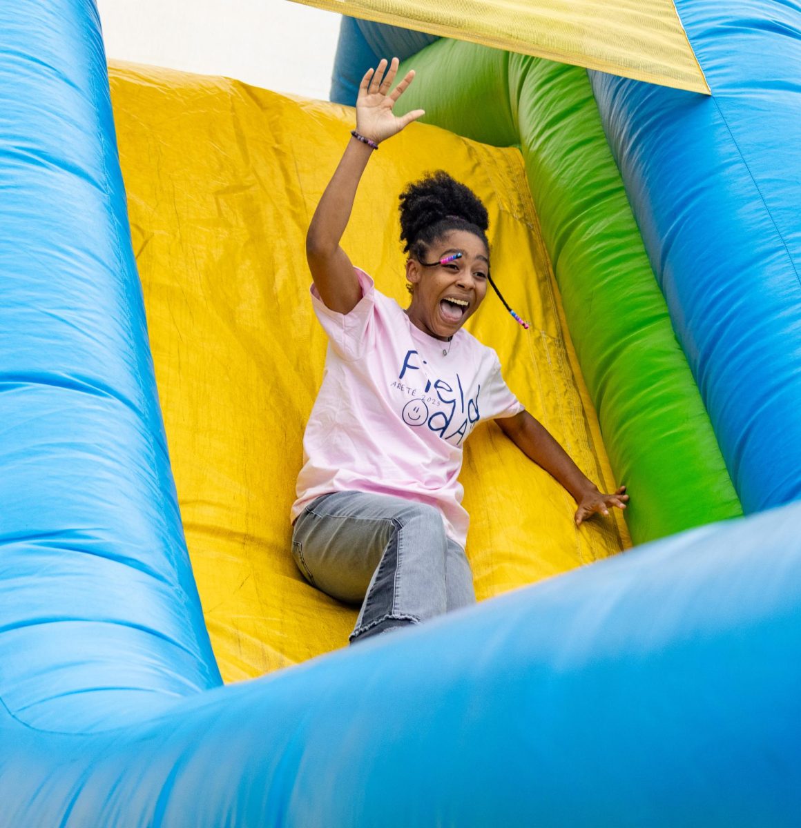 Holding her arms in the air, junior Kate Hewing screams in joy as she glides down the slide. Hewing has attended the Arete Field Day for the past three years, as well as the Arete breakfast they host in the fall. 