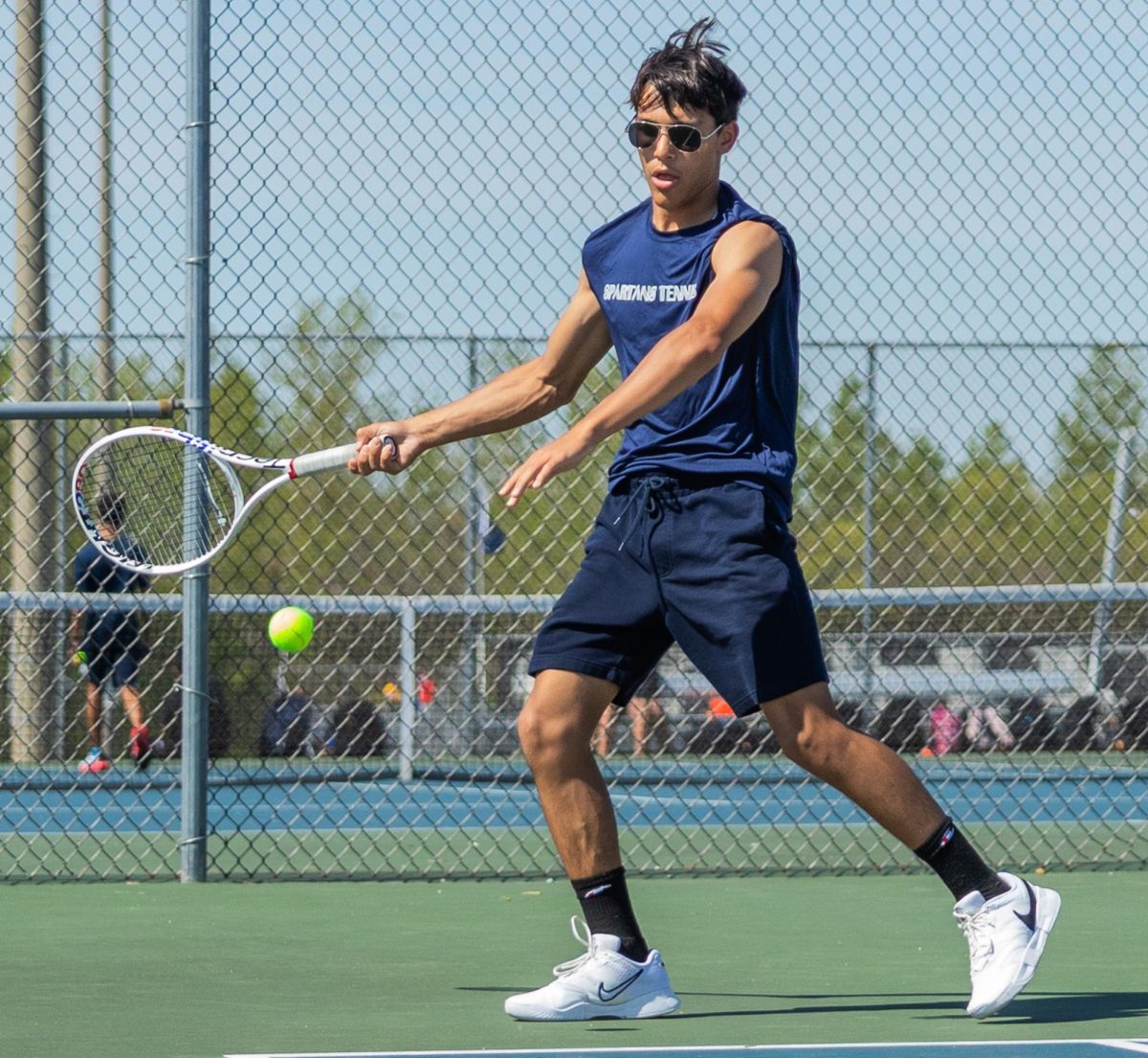 Junior Vincent Castille moves to hit a forehand to his opponent. With his feet in position, he aims the ball back across the court.