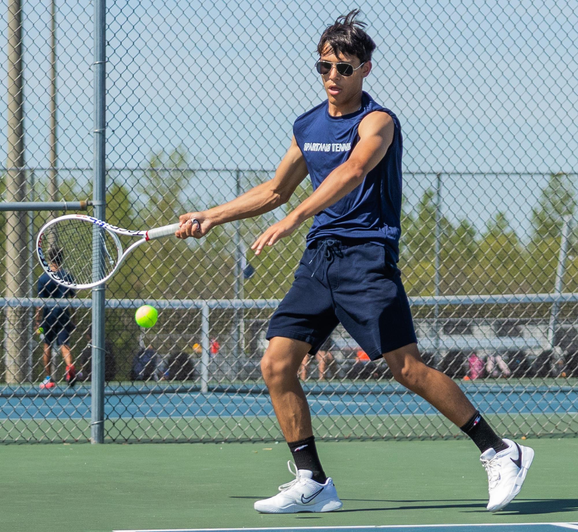 Junior Vincent Castille moves to hit a forehand to his opponent. With his feet in position, he aims the ball back across the court.