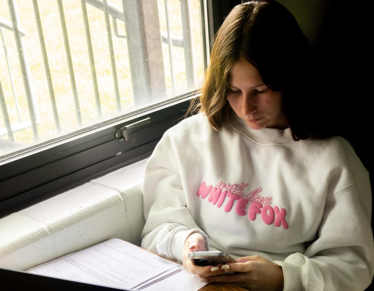 Senior Carrie Byrne sits on her phone during her third period AP Psychology class. In an email to district staff and families, an new phone policy was announced to "reduce distractions in the classroom."