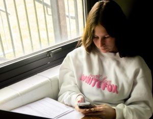 Senior Carrie Byrne sits on her phone during her third period AP Psychology class. In an email to district staff and families, an new phone policy was announced to "reduce distractions in the classroom."