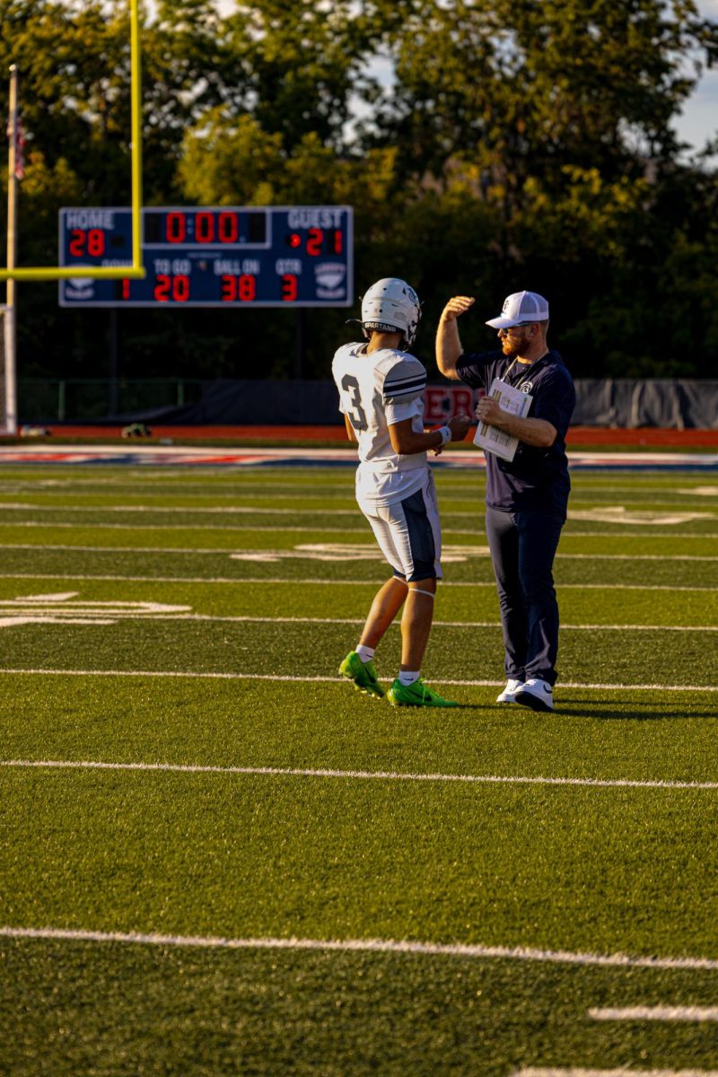 Coach Jacob Mattson calls freshman quarterback Sam Aholt to get the play to start the drive. This was a crucial moment for the Spartans, they have to score here to tie the game. 
