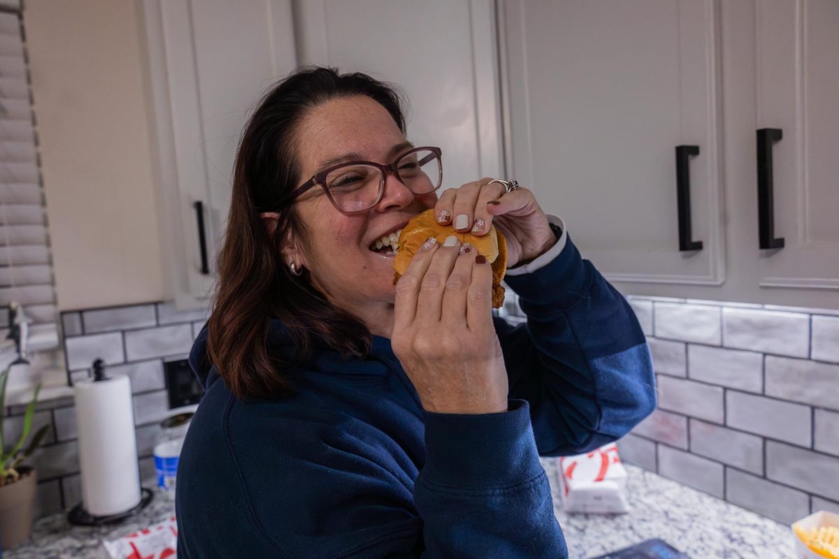 Mrs. Raziq is eating a Chick-fil-A sandwich. She is enjoying her sandwich and talking to Amelia Raziq.