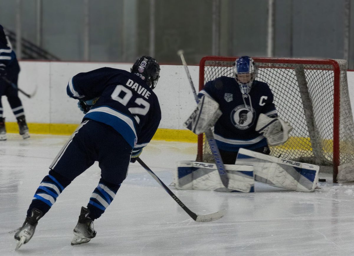Junior Patrick Davie shoots on goalie senior Tyler Vonfeldt during the team’s warm ups. The team shoots on their own goalie to practice their shots before the game.
