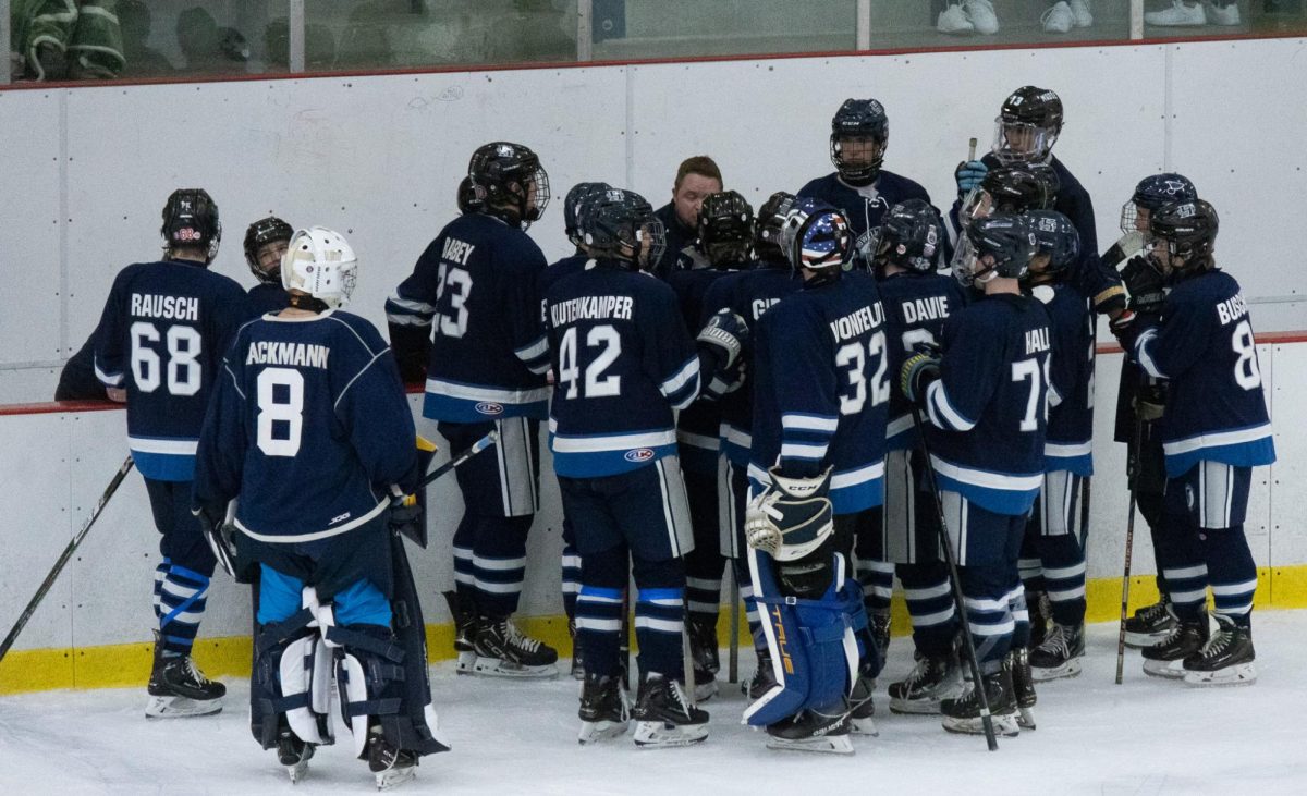 Before the start of the third period varsity hockey gathers around the coach. They listen to what they could do better going into the last period.
