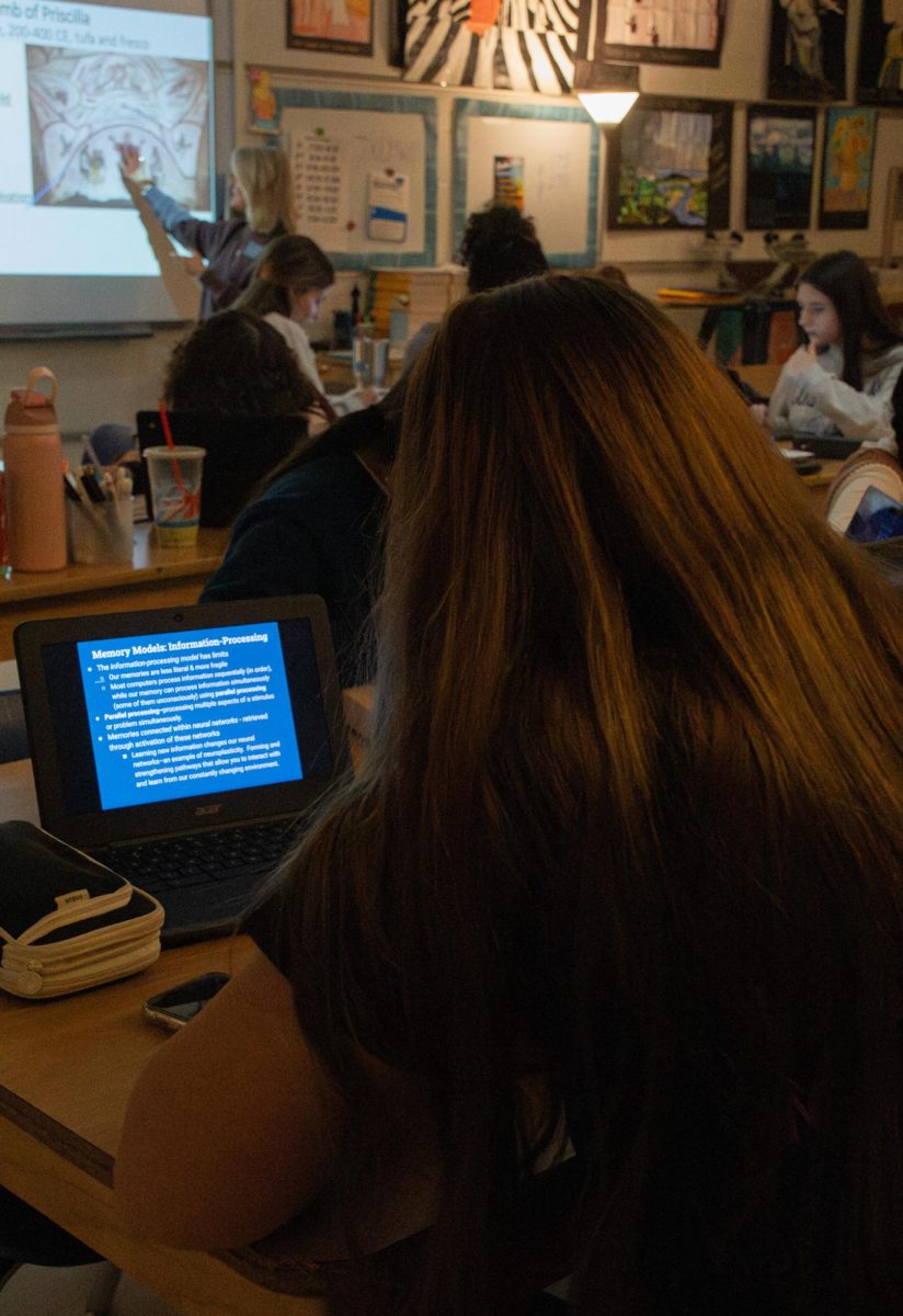 Junior Izzy Dunlap, intensely studies in her AP Art  History class while Mrs Michelle McCune lectures in the background.