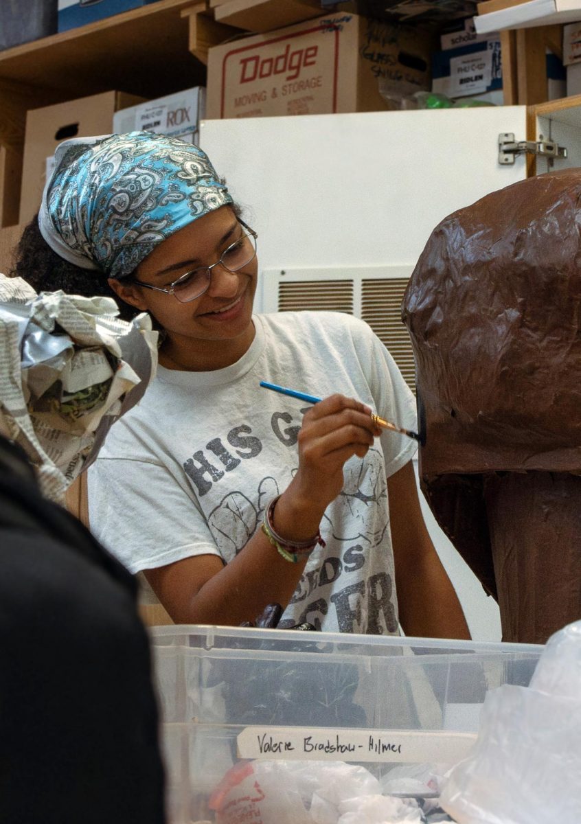 Senior Baylee Spraggins applies brown paint to the sculpture of Malcolm X's head. Spraggins hopes that the final result of their project will depict Malcom X as a caricature. 