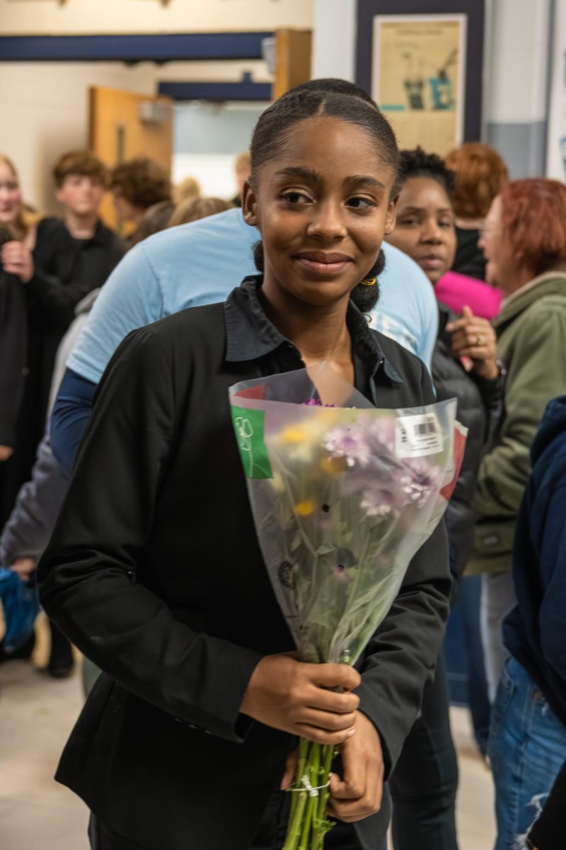 Senior clarinet player Kate Hewing holding flowers looking for her peers on Dec. 9. Hewing was then greeted by an ecstatic family happy with her performance. 