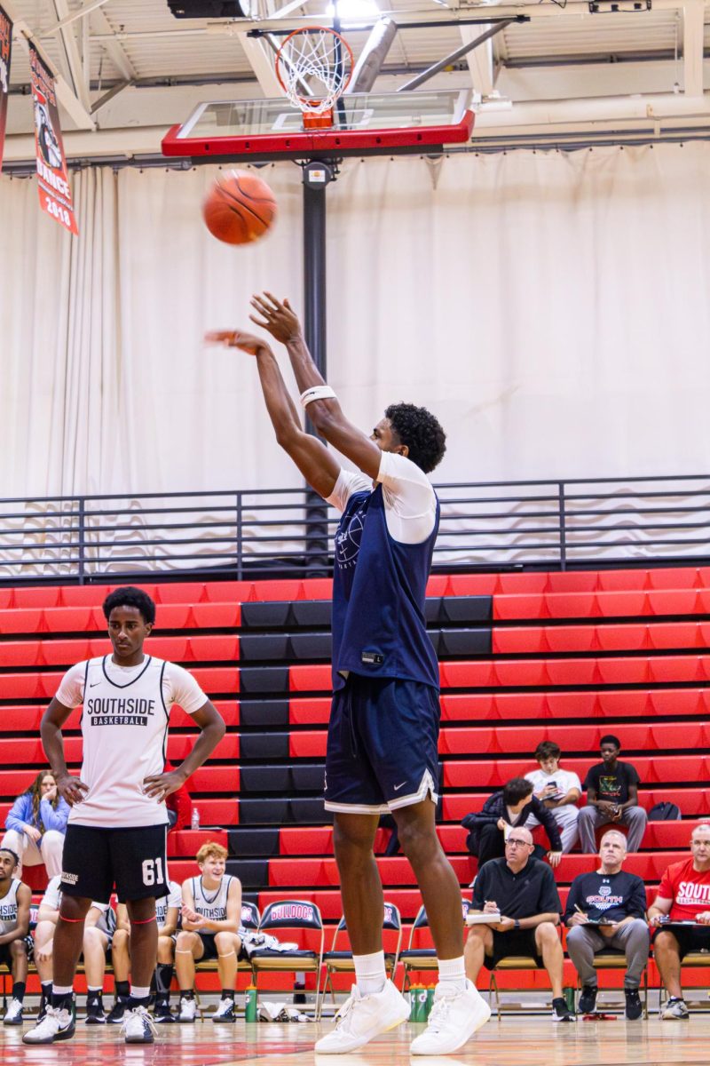 Shooting with ease on Nov. 20, Senior Xavier Morrison throws the ball to the hoop on the free throw line. People in the stands, players on the other team, teammates on the sidelines and those on the court watched while they anticipated when Morrison executed the ball into the hoop successfully. 