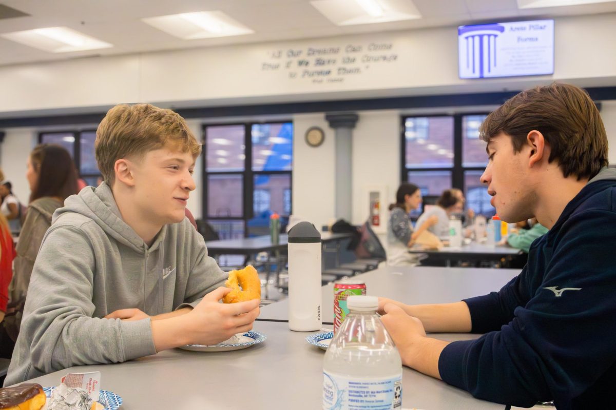 On Nov. 21 at the Arete breakfast, juniors Josh Hadden and Colton Jones talk over donuts. Once they got their breakfast they sat down and talked before the ticket drawing.