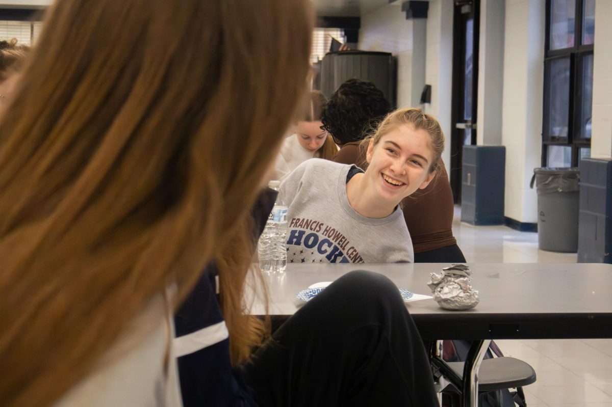 Junior Mackenzie Uglum talks to junior Rachael Latzel during the Arete breakfast on Nov. 21. Uglum laughed after Latzel made a funny remark.

