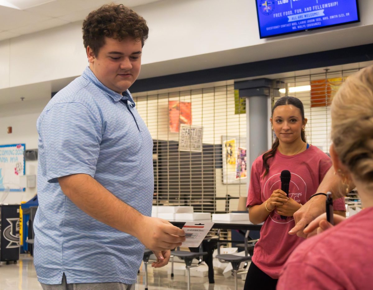 Senior J.J. Hollywood grabs a Chick-Fil-a gift card from the table of prizes. After his number was called out, he ran up in excitement to make his choice.
