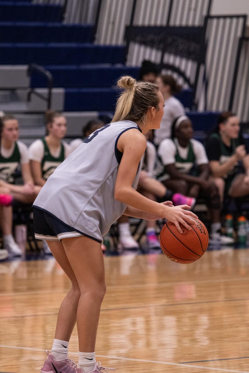 Lined up in front of the hoop, freshman Molly Hill dribbles the ball. She's surrounded by her own teammates and opposing ones on Nov. 18, yet she doesn't let this affect her focus. 