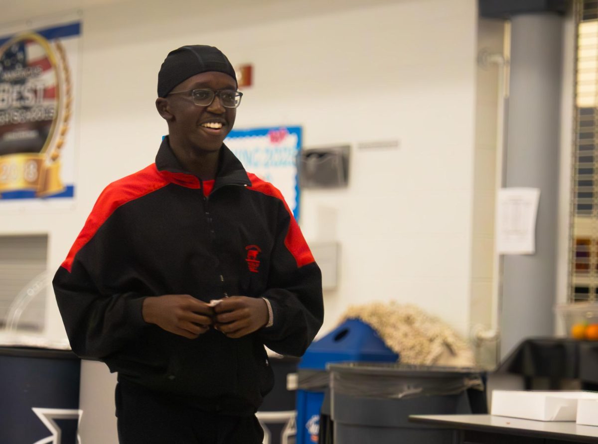 Junior Ethan Oketch walks up to pick his prize during the Arete breakfast on Nov. 21. After the gift card prizes ran out, he went to choose a t-shirt instead.