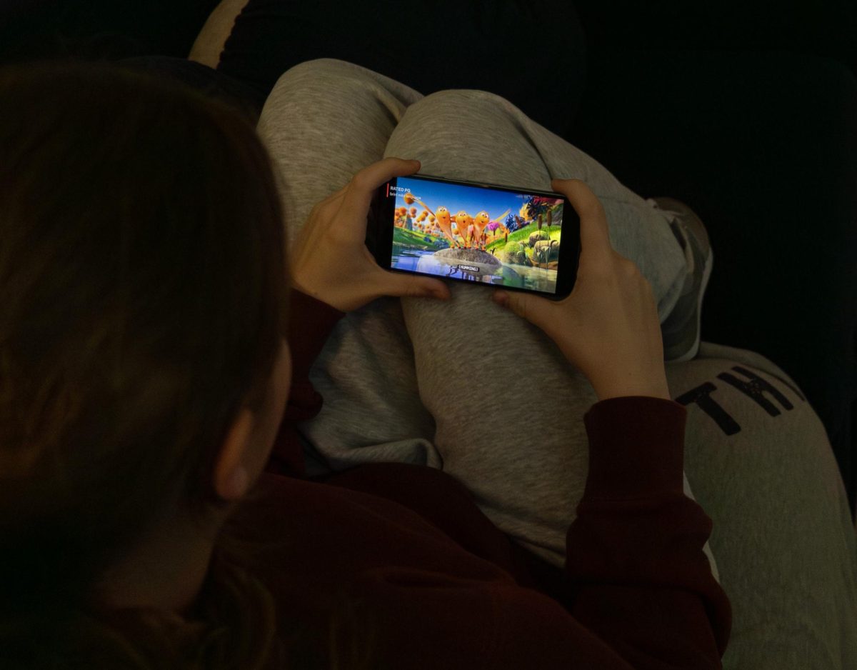 Lillian Richter is seen watching a movie cozily from her phone. This is just one of the many ways students enjoy media.