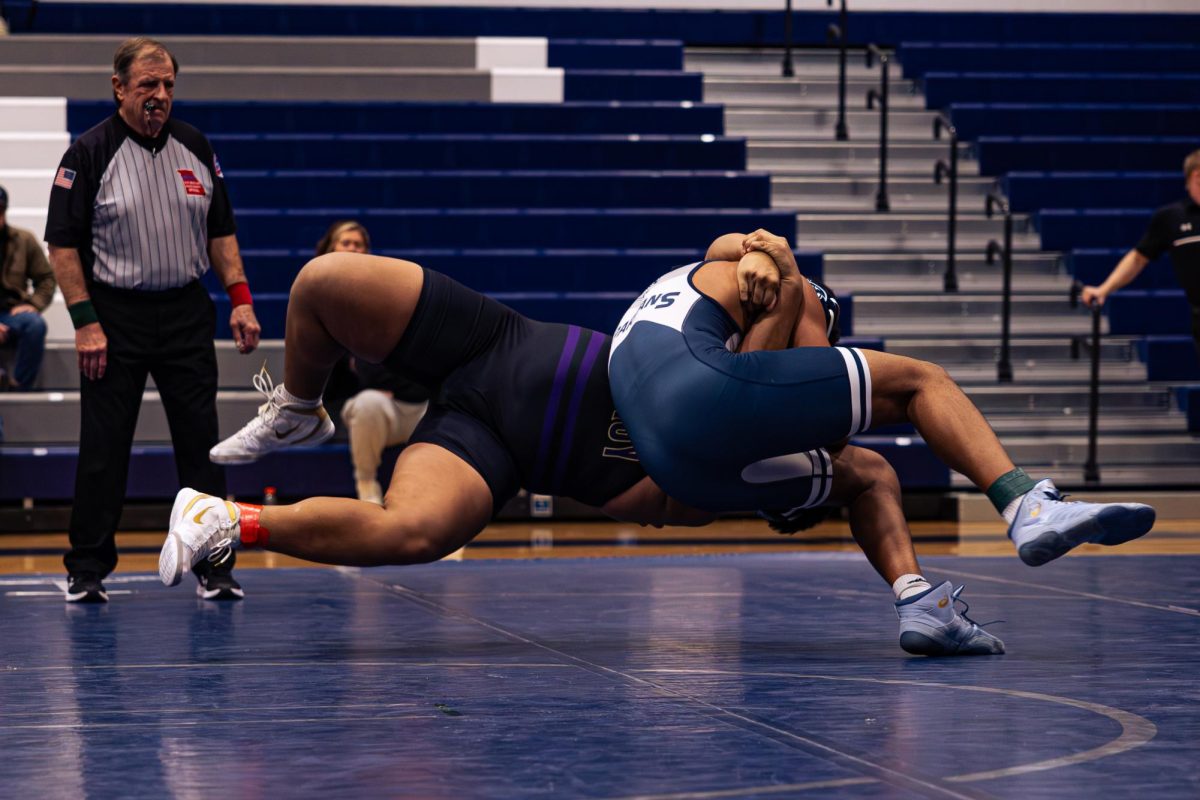 Garo Sams is mid-air, about to slam his opponent down and pin him on Jan. 21. This was the team's last home game for the season, meaning it's the last home game for all seniors this year.