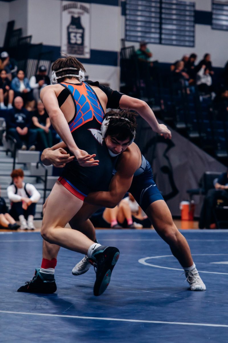 Driven with efforts to dominate, junior Isaac Lecca wraps his arms around his opponent on Jan. 7. In quick succession, Liberty's wrestler was then slammed on the mat.