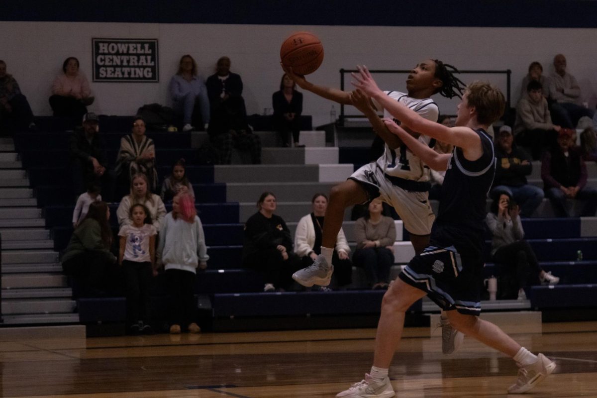 Freshman Hayden Emery battles the Crusaders defender as he goes up for a shot on Jan 13. He reached past the defender and the shot went in the basket, adding two points to the score. 