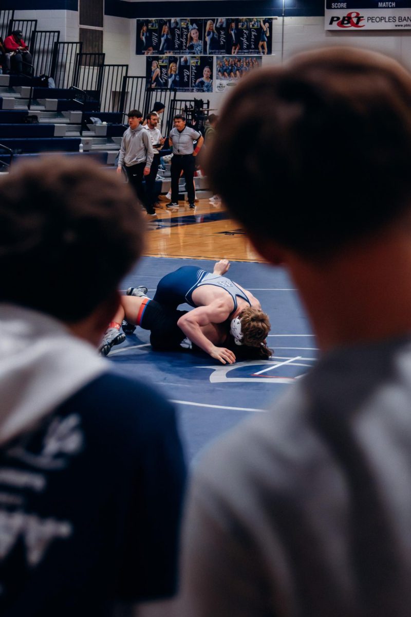 Wrestling managers observing Sam Golden pin his opponent. Throughout the match managers cheered on Central players which helped lift morale.