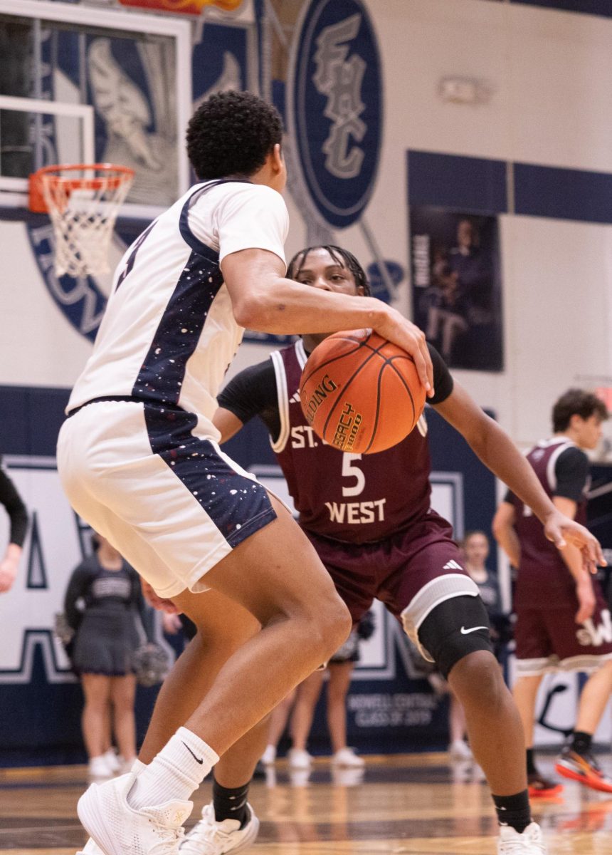 Having a clear goal to get across the court on Jan 20. inching closer and closer to the hoop. Junior Jamarious Britt guarded the basketball that was in his hand as he was blocked by a player on the St. Charles West team.