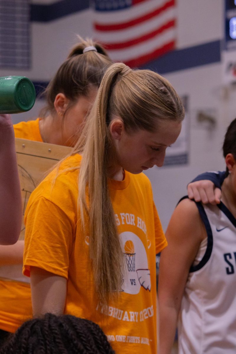 During a timeout the team gathers around to look at the coach talking on Feb. 17. Junior Elle McDevitt watches as the coach talks so she learns plays and the right ways to win in a game.