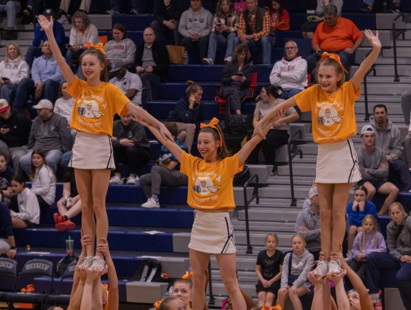 Halftime starts and the varsity cheerleaders perform their routine on Feb. 17. The flyers get lifted up and grabbed onto each other's arms for support and waved to the audience.