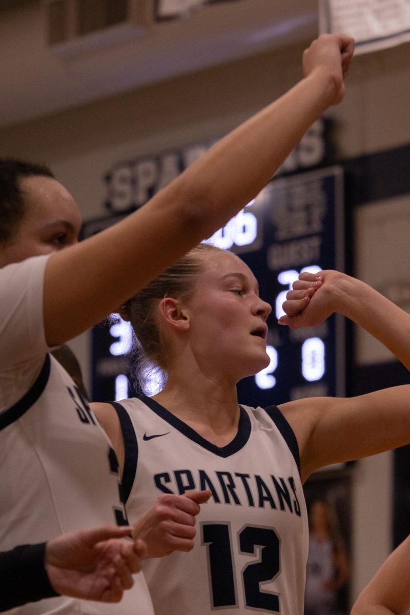  After a time out, junior Mikaela Bond makes a fist and puts her arm in the middle of the team. They all did a chant together and then went back to playing on Feb. 17.