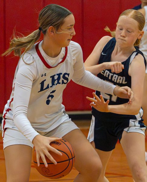 Liberty’s athlete dribbles the basketball between her legs guarding it, while freshman Chloe Bond puts her hand through the girl’s defensive block. Bond fought for dominance of the ball, more often than not with this specific opponent.