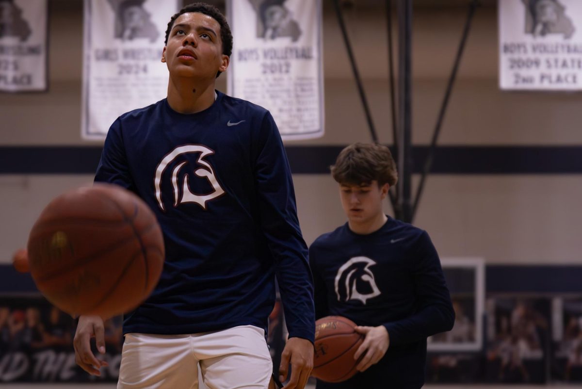 Beginning the warm-ups on Feb. 20, junior Jamarious Britt and his teammates practice their drills to prepare for the game. Britt dribbled the ball and passed it along to his teammate.
