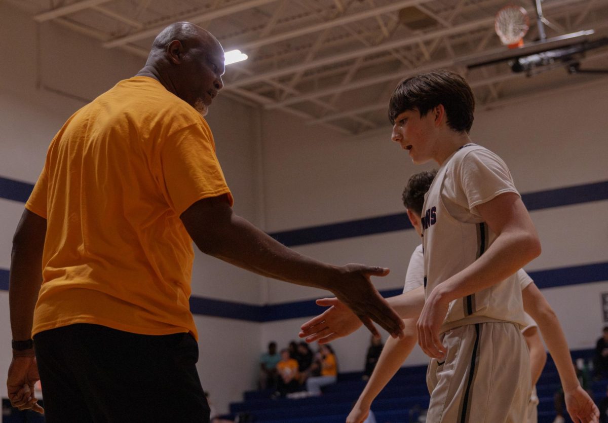 After a successful play, Coach Terrance Harris high fives sophomore Lucas Miller as he comes off the court on Feb. 17. Another player then made their way onto the court, continuing the game.
