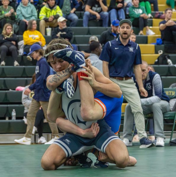 Sitting back on his knees, senior Chase Gray works to get the North Point wrestler on the mat and get his three points. Gray hooks his hands on his opponent's ankle and tries to get him flat on the mat.  