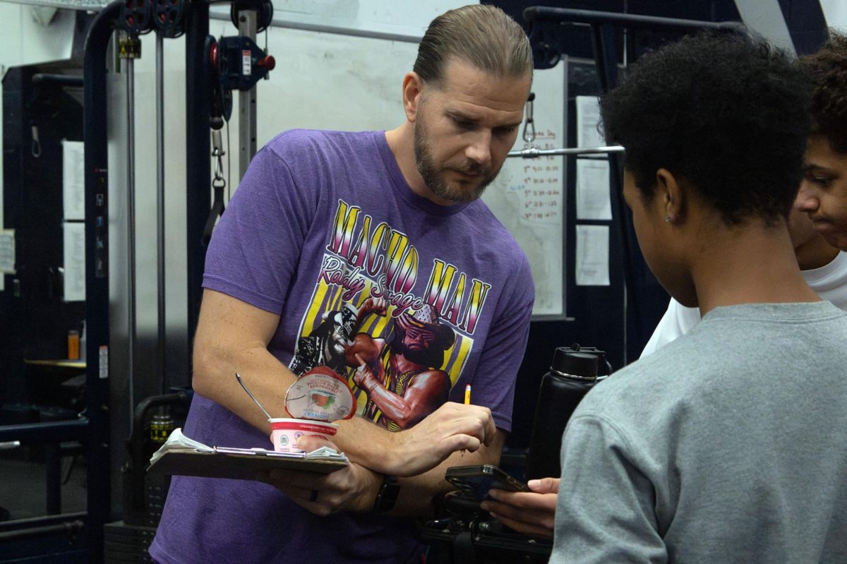 Carter signs off on students' max outs. His dedication to his body translates to his dedication as an educator, leading the new generation to be fit and healthy.