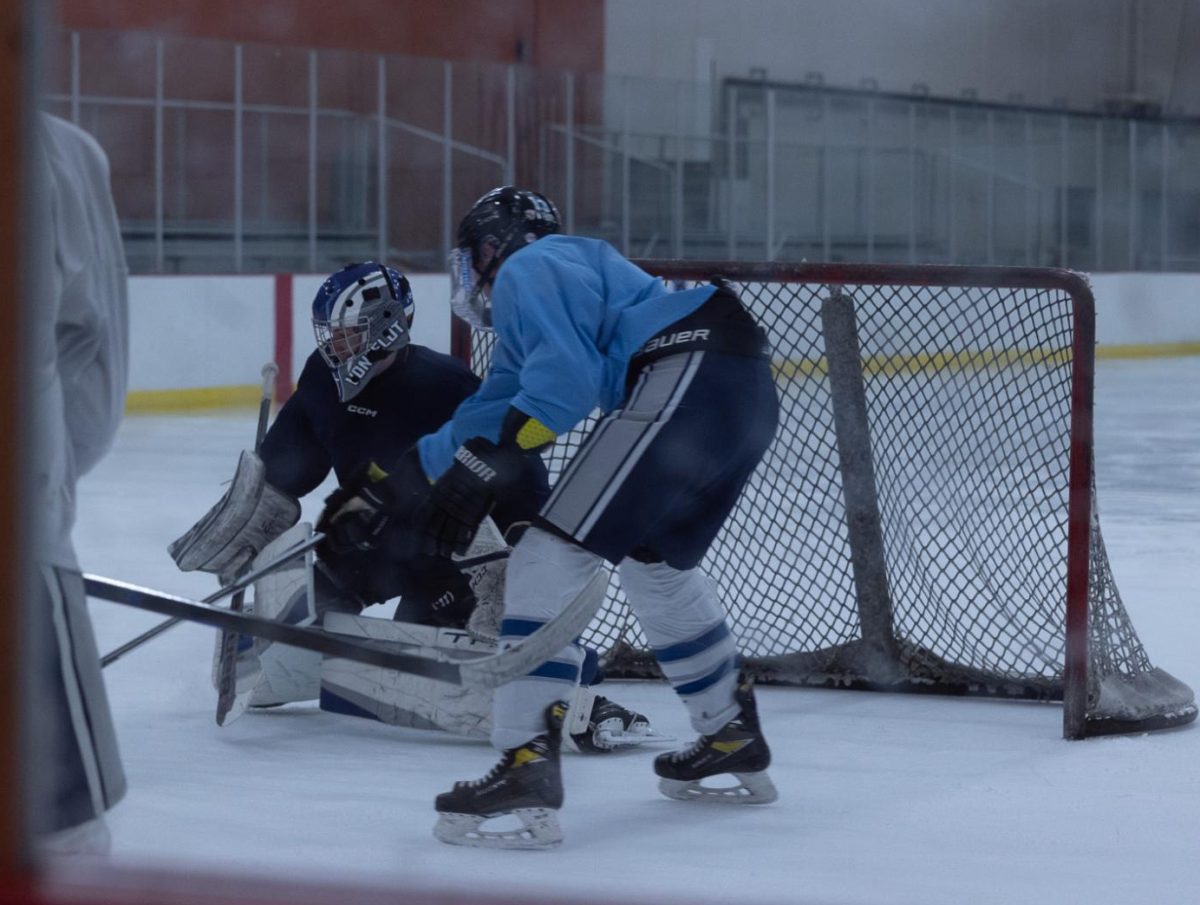 Senior Tyler VonFeldt protects his team's goal while driving the puck away. But, his opponent Jase Thomason, strives back, making the game challenging. 