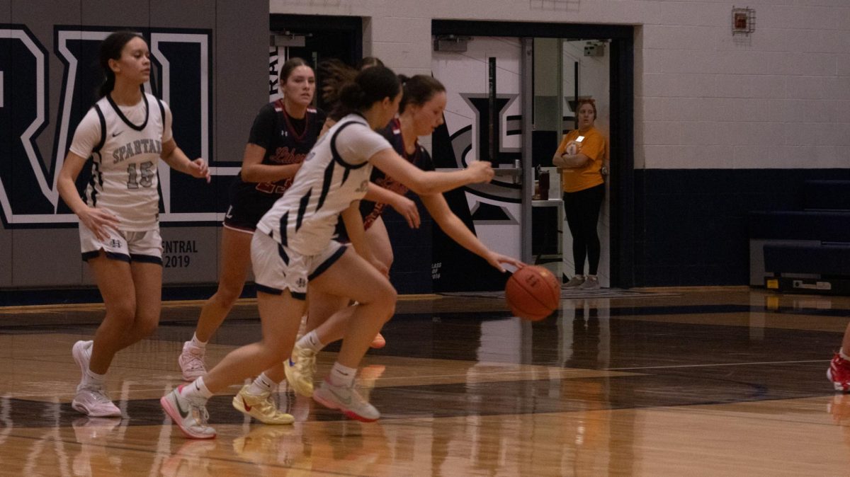 As the liberty player takes the ball down the court on Feb. 17, sophomore Eva Trotter moves around her trying to grasp it from her opponent. The game is full of intense moments were players are caught between opponents and attempt to make a play.