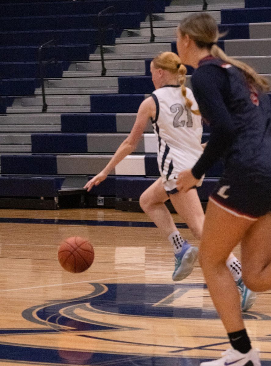 Dribbling the ball as she runs down the court, freshman Chloe Bond makes a breakaway. On Feb. 17, she bypassed all of the liberty players and attempted a shot on the basket.