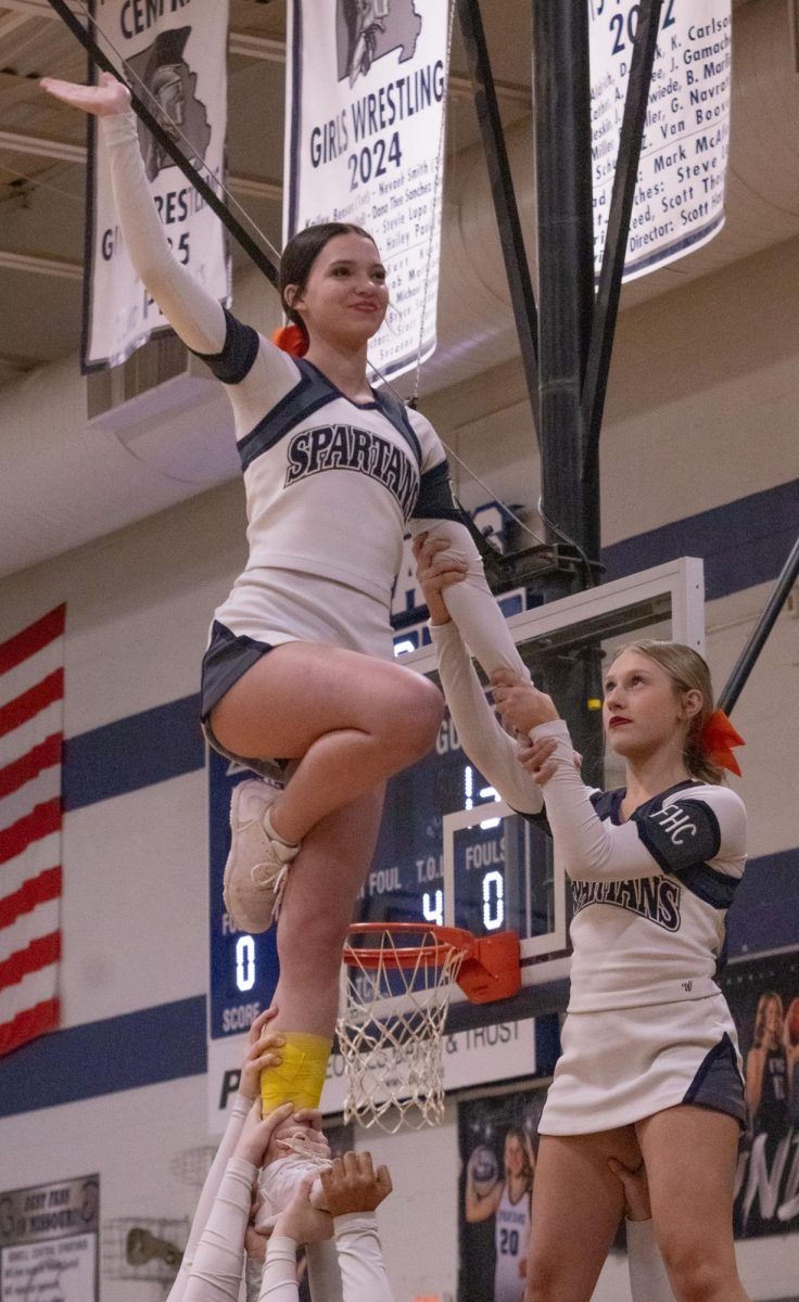 Sophomore Makayla Delllacca stands tall above the crowd as her bases hold her up on Feb. 17. She smiles out at the fans sitting in the bleachers and waves proudly.