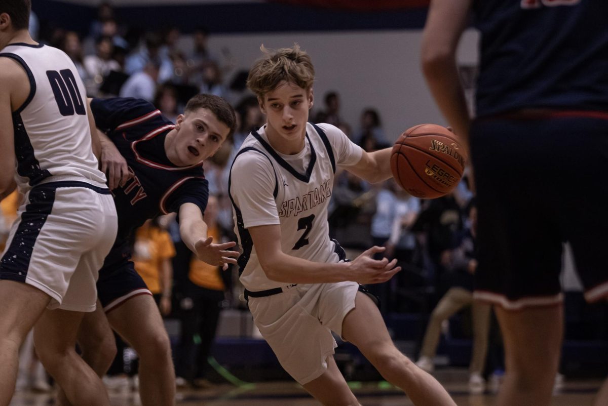 Junior Jack Brown sets a screen for junior Ryan Halterman, allowing him to slip past during the game on Feb. 17. The defender reaches out in a futile attempt to stop Halterman from scoring.