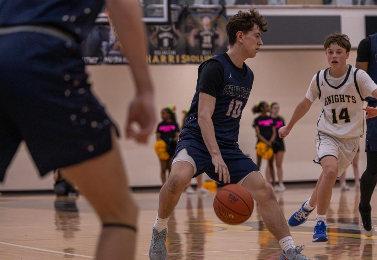 Junior Jayden Tucker Dribbles the ball in between his legs on Mar. 27. Tucker is attempting to hold off one of Howell North’s defenders.
