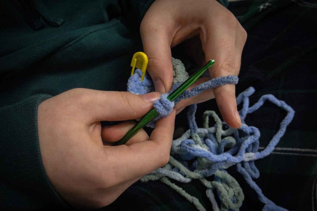 Freshman Kyle Baumann crochets with teal thread. He is among the students in theatre who are creating the thread art for the "Into the Woods" production.