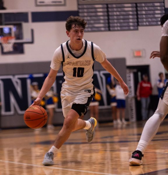 Junior Jayden Tucker dribbles the ball around a Howell defender on Mar. 5. Senior Xavier Morrison set a screen to allow Tucker around the defender.
